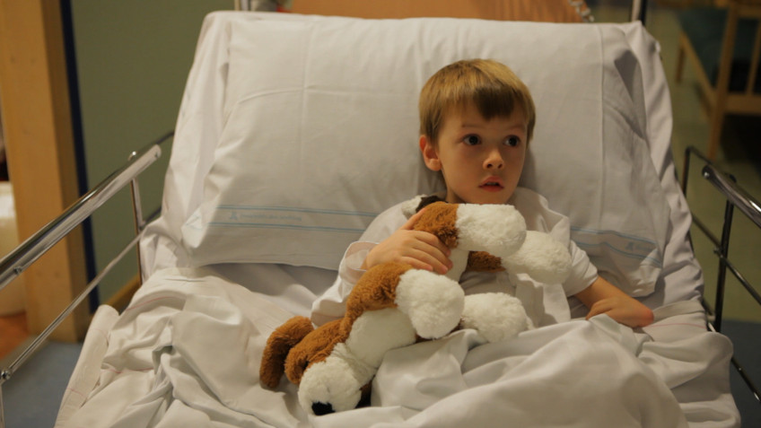 pojke i sjukhussäng ur clownmedicin på Astrid Lindgrens barnsjukhus Karolinska