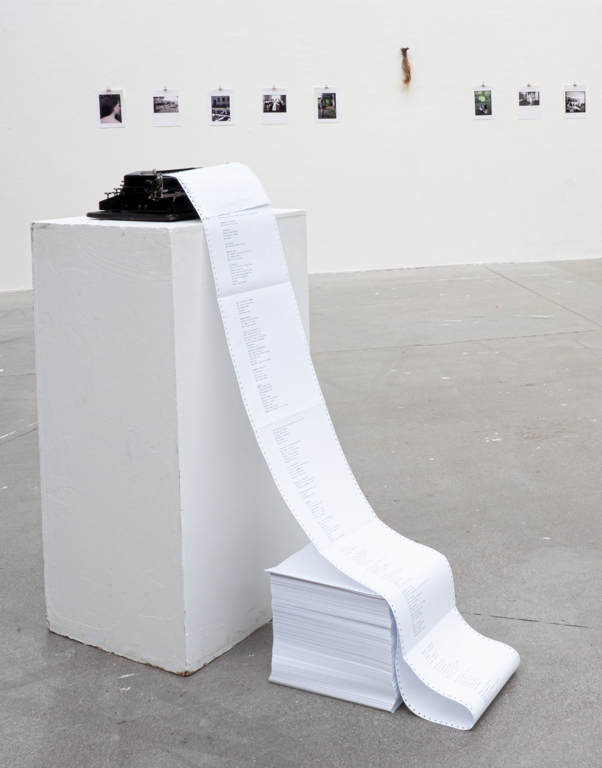 Skrivmaskin på podium med en lång remsa tabulatorpapper som hänger ner och bildar en hög trave med A4-papper